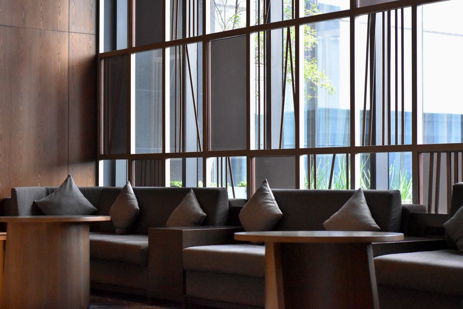 Contemporary lounge with sofas, tables, and large windows in Guadalajara hotel lobby.