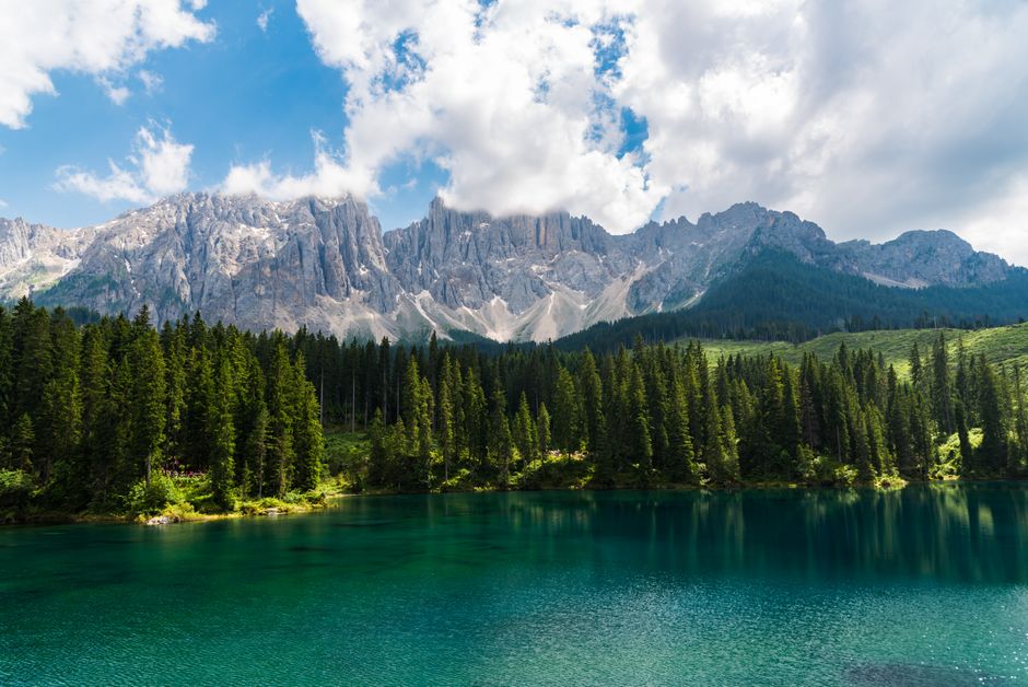 Breathtaking view of emerald lake surrounded by Dolomites and lush forest in Italy.