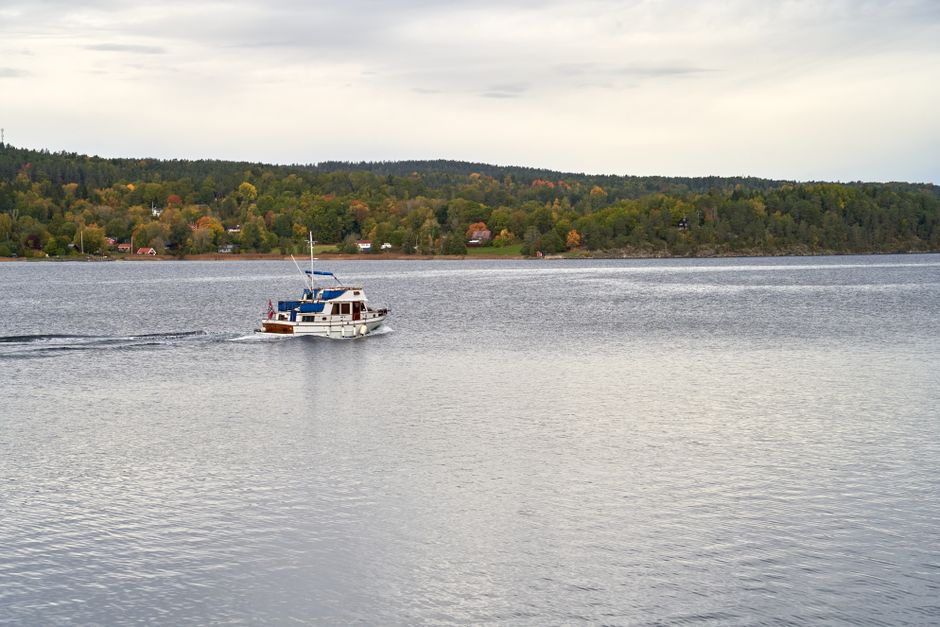 A serene cruising yacht gliding across Bunnefjorden in Akershus, Norway during fall.