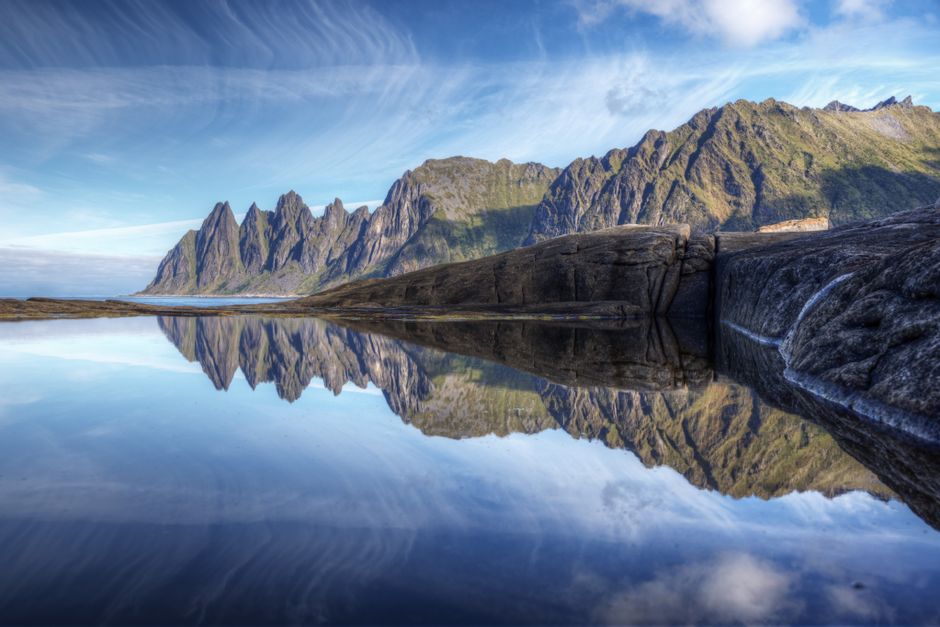 Capture of Segla Mountain reflecting in clear waters of Norway, showcasing its sharp peaks.