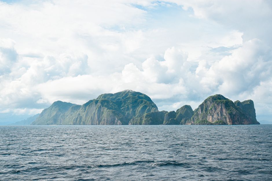 Stunning landscape of an island in the sea under cloudy skies, perfect for travel inspiration.