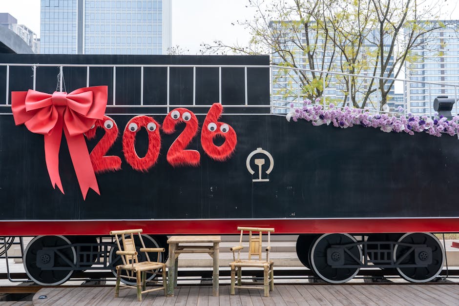 A festive train decorated with '2026' and a red bow, set in an urban environment.