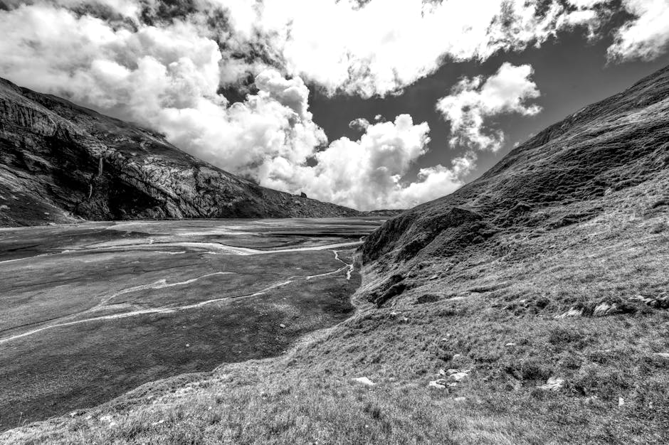 Striking black and white photo of the Swiss Alps with dramatic clouds and rugged terrain.