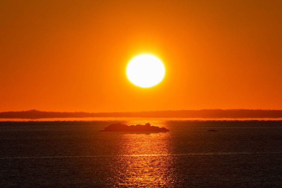Stunning sunset view over Stamford Harbor with a fiery orange sky reflecting on the ocean.