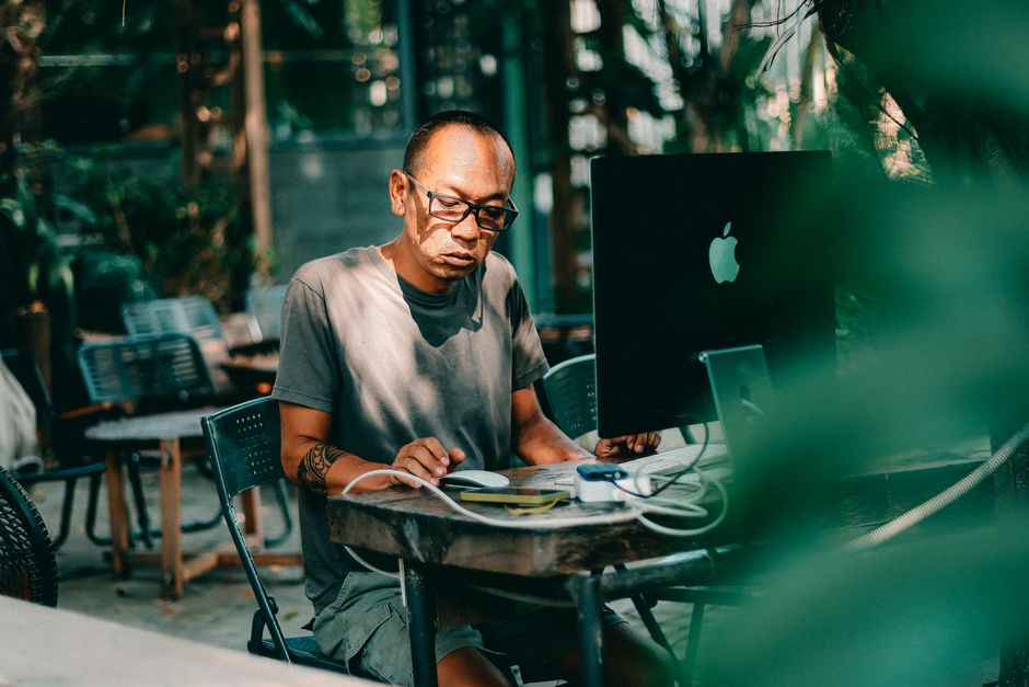 Focused man working on a computer in a peaceful outdoor setting.