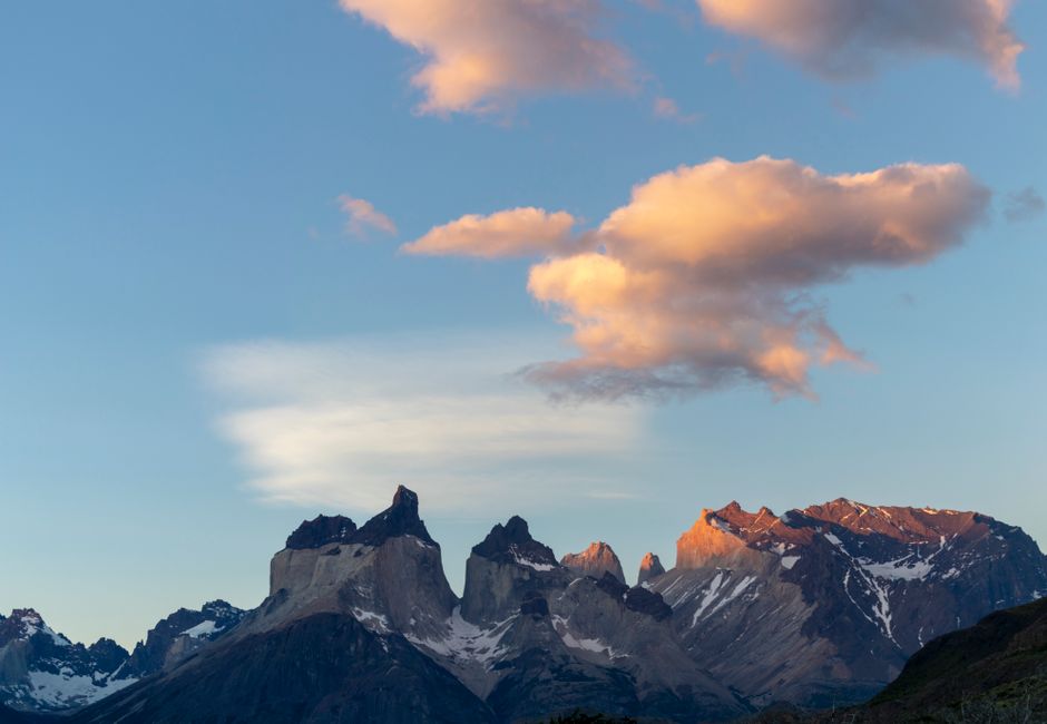 Scenic view of a mountain range under a sky with soft clouds, captured at sunset.