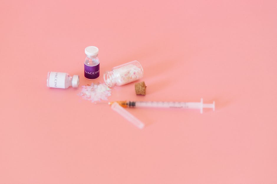 Conceptual image of vaccine vials and syringe on a soft pink background.