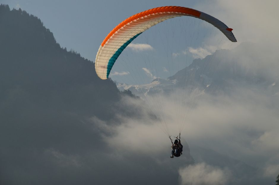 Paraglider sailing through clouds above the Swiss Alps near Lucerne, capturing adventure and tranquility.