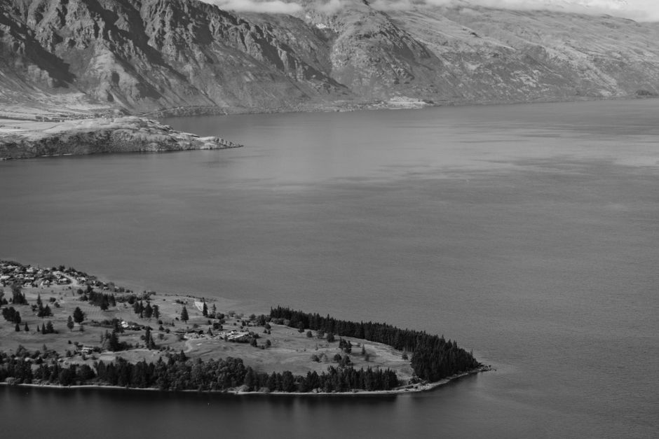 A serene monochrome aerial view of Lake Wakatipu with surrounding mountains in Queenstown, New Zealand.