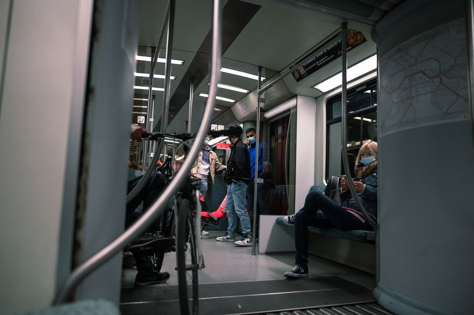 A group of masked passengers on a modern subway train practicing social distancing.
