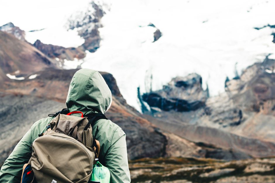 A hiker in a green jacket explores the breathtaking mountains of Jasper, Alberta.