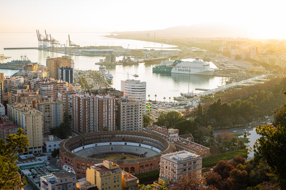 Stunning aerial shot of Malaga featuring the bullring and busy harbor at sunset.
