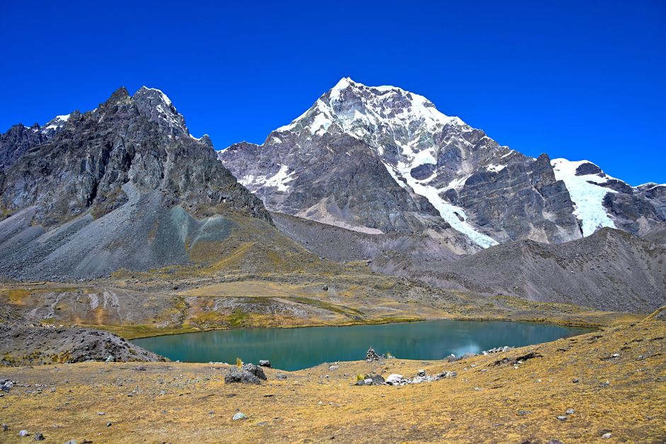 Stunning view of snow-capped Andes mountains with a serene lake beneath, captured in vibrant daylight.