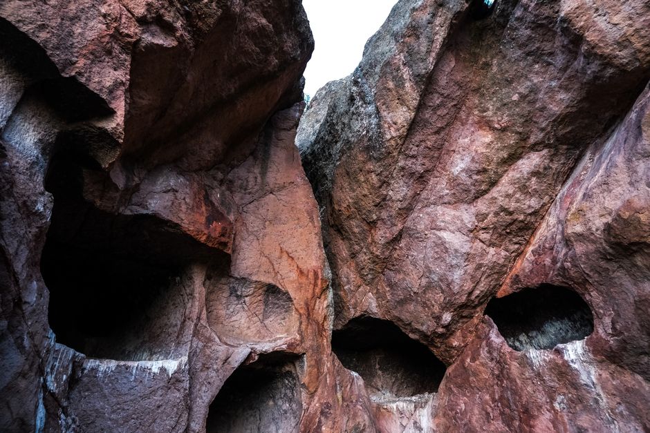 Impressive red rock formations with natural cave openings creating a dramatic landscape.