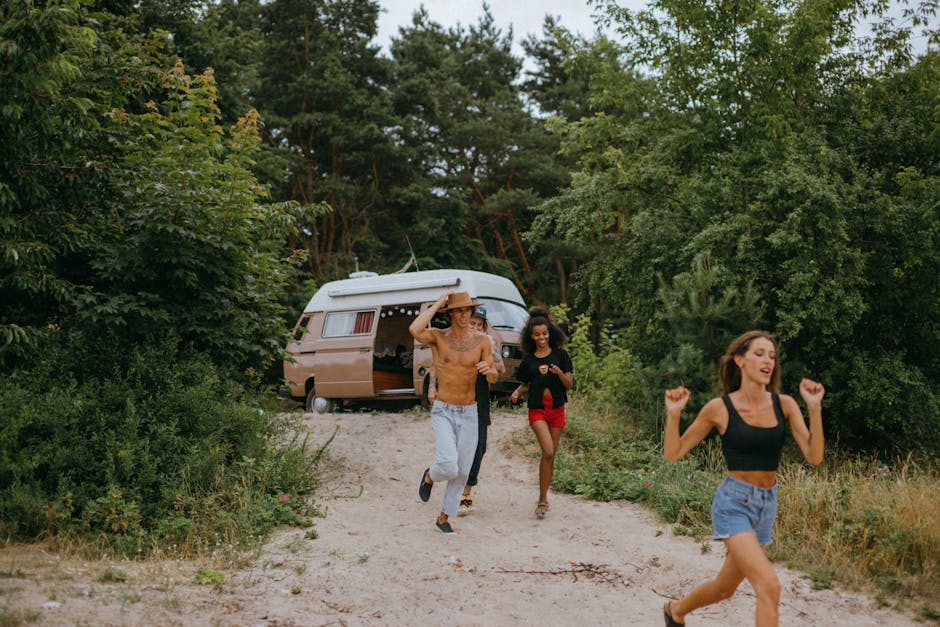 Energetic friends running near a camper van in a lush forest, enjoying a summer adventure.