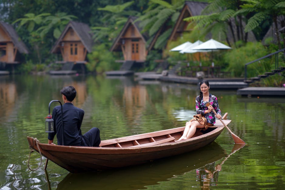Couple enjoying a peaceful boat ride at a picturesque lakeside resort with cabins.