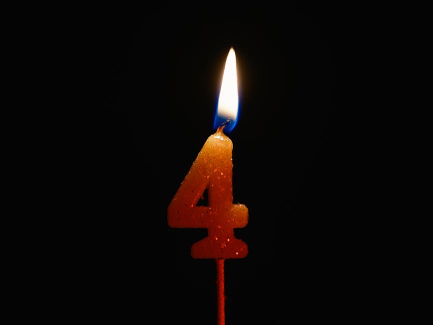 A lit number 4 candle against a black background, perfect for birthday celebrations and anniversaries.